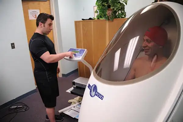 一名男子正在使用空气置换体积描记法(Bod Pod)进行精准的体成分测量。