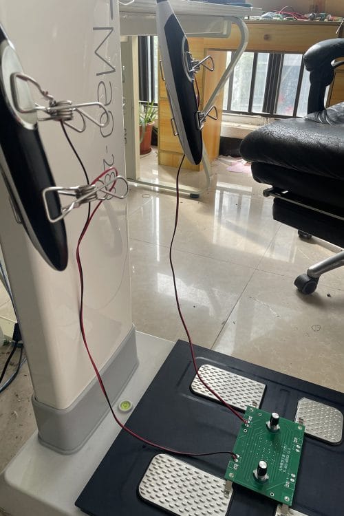 完整的系统校准场景，展示了iBodyinfo 人体阻抗校准工装如何同时连接分析仪的手部与脚部电极。